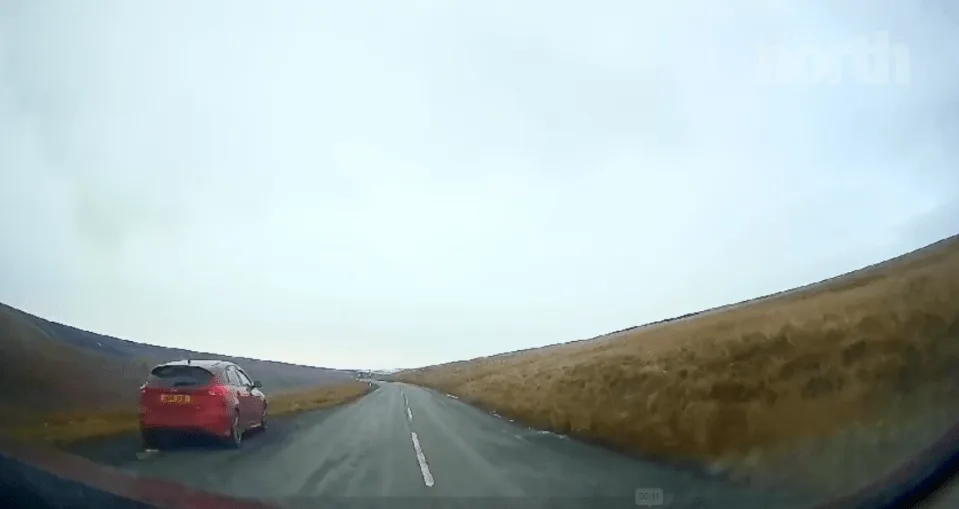 Car voiture rouge s'est garée sur une route.