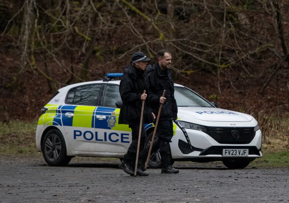 Des policiers fouillant une forêt.